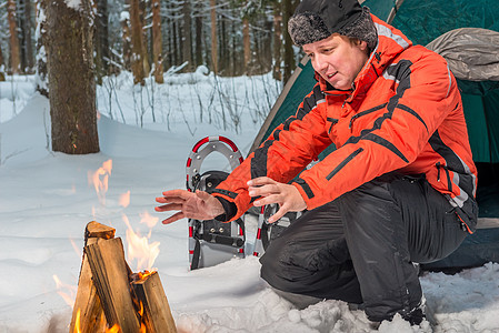 游客在冬季森林的火炉附近暖暖他的手图片