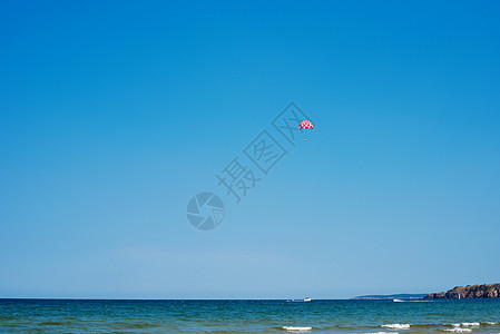 在海上跳伞 用船拖着 在晴朗的天空中滑翔伞 骑在船后的降落伞上图片