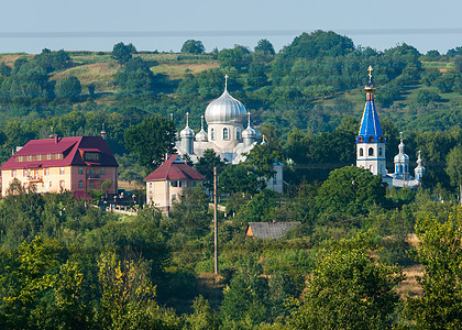 在绿色山坡的背景下 教堂的顶部有五颜六色的屋顶和圆顶图片