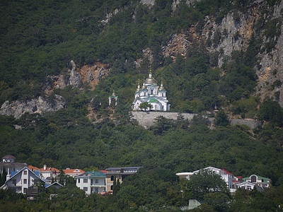 一座有绿色屋顶和圆顶的画像教堂 其背景是绿岩山图片
