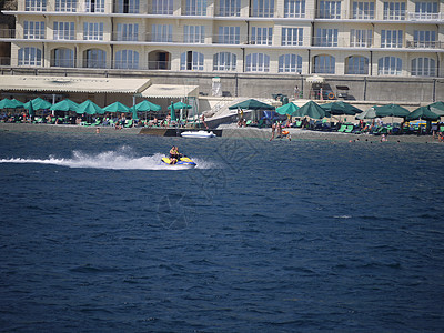 旅馆附近有带绿色雨伞的沙滩 旅游者骑水车图片
