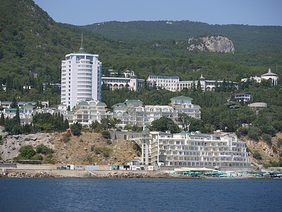 海岸风景如画 山坡上长满了茂密的绿色森林 山上矗立着城市房屋和酒店图片