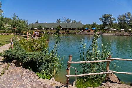 一个大池塘 小径周围铺着石头 人们在周围美丽的风景和蓝天的背景下行走图片