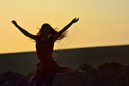 少女在美丽的夕阳下跳跃 草 享受 高的 成功图片