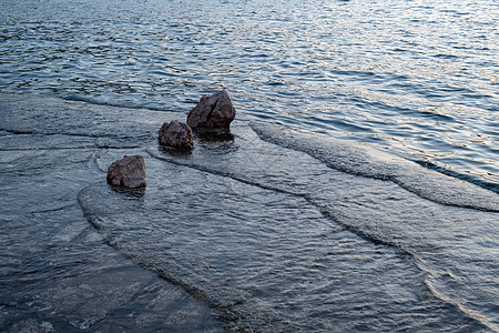 海滩冷日落 小海浪用岩石撞到海滩图片