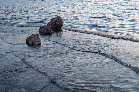 小海浪在日落时用岩石撞击海滩图片