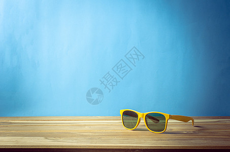 太阳镜用蓝色背景放在木地板上 夏季的饰品图片