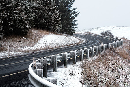 通过雪覆盖的山丘弯曲道路图片