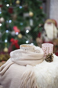 热巧克力 一杯卡布奇诺 在一棵大圣诞树前的毛皮椅子上 带球和灯光的火辣果 装饰品 舒适图片