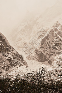 白雪皑皑的山峰 冬天结冰的喜马拉雅山谷景观 美丽的风景与雪山和树木 在雪盖的前景的杉木森林在冬季图片
