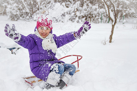 在公园里玩雪花的滑雪小姑娘图片