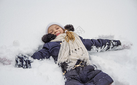 女孩躺在冬季公园的雪上图片