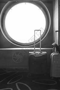 在船的圆形舷窗前旅行的两个手提箱 休闲或商务旅行的概念 垂直拍摄图片