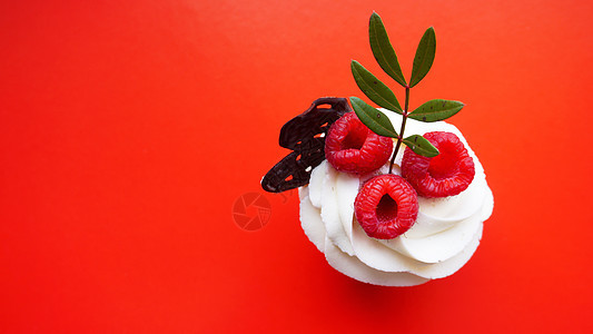 甜点心 带奶油的纸杯蛋糕和红色背景中的覆盆子 甜的 生日图片