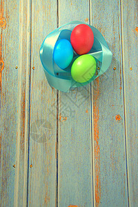 木桌上放着三个带蓝色缎带的复活节彩蛋 春天图片