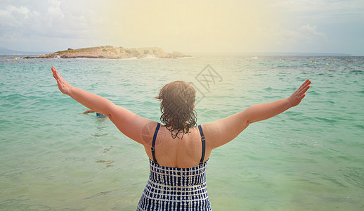 嗨 夏天快乐的年轻女子穿着泳衣 双手举起 享受海边日出 海滩暑假概念图片