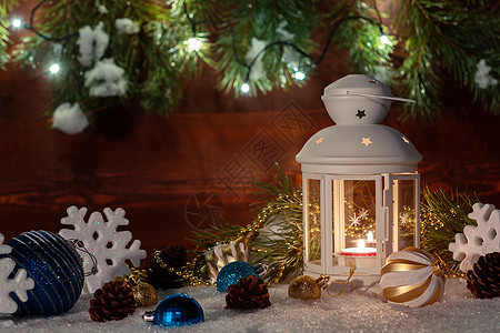 雪地上放着燃烧着蜡烛的白色灯笼 周围环绕着木墙 圣诞树枝和灯的圣诞装饰 球 季节图片