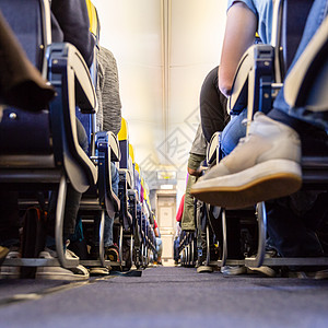 商业飞机过道的低角透视消毒者 在飞行时有消毒者坐在座位上图片