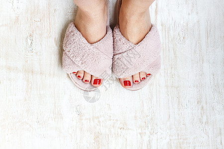 双脚和红指甲 在家庭毛毛 毛毛的粉红色拖鞋上 美甲 衣服图片