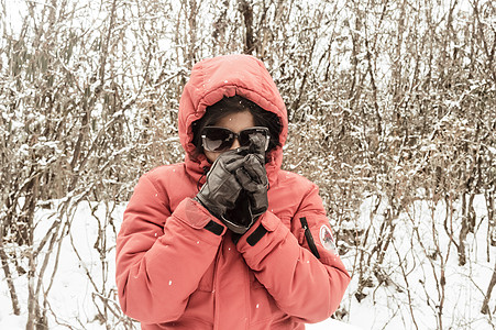 一个穿着红色套头夹克和手套的女人微笑着快乐地享受着第一场雪 同时抖落了雪球 在冬天享受下雪天的景色 农村查谟和克什米尔 大裂图片