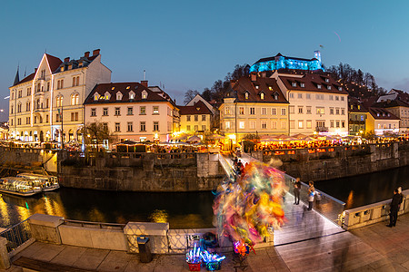 古城中心的Ljubljanica河岸景象充满活力 市中心在黄昏时装饰着圣诞灯 旧中世纪的Ljubljana山丘笼罩了城市 斯洛文图片