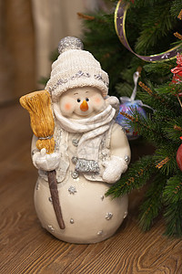 傍晚时分 圣诞树旁拿着扫帚的滑稽快乐雪人 自制的节日温馨气氛 正视图 垂直的图片
