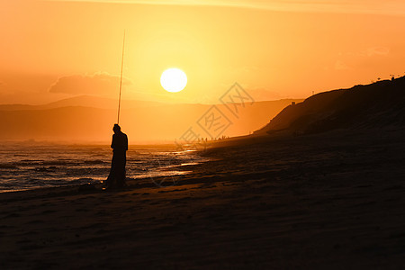 日落海滩上的钓鱼图片