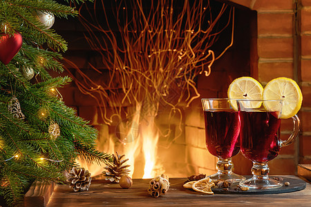圣诞装饰 - 在燃烧的壁炉对面一棵圣诞树附近的木桌旁 两个杯子上挂着面包红酒 仔细考虑 火焰图片