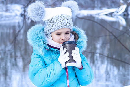 冬天户外的小女孩从杯子里喝茶 一个可爱的女孩在户外喝一杯热茶的肖像 冬季 女性 热的图片
