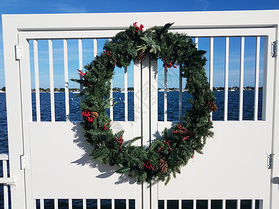 白栅栏和水上的假日圆花圈 海 圣诞节 松果背景图片
