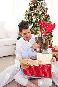 喜笑的父亲和女儿的复合形象 开启圣诞礼物;在圣诞节开礼图片
