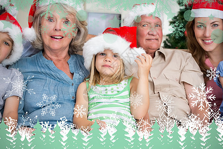 多代人幸福家庭在沙发上戴圣诞老人帽子 祖母图片