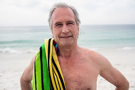 快乐的高级男子站在沙滩上 肩膀上有毛巾 自由图片