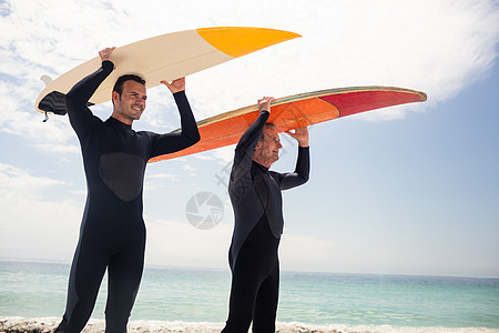 快乐的父亲和儿子带着冲浪板 在他们的头上图片