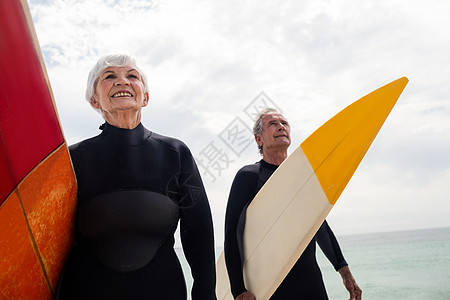 穿着湿衣的老夫妇在海滩上持冲浪板 浪漫的 老年图片