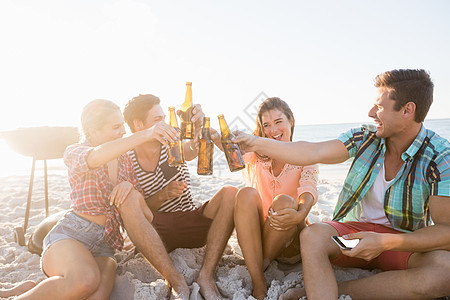 微笑的朋友们欢呼着啤酒 休闲服装 喝 快乐的 享受 海滩图片