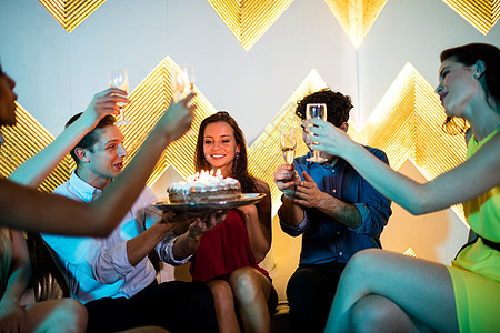一群笑笑的朋友们在庆祝生日时 为一杯香槟举杯敬酒 酒吧 喝图片