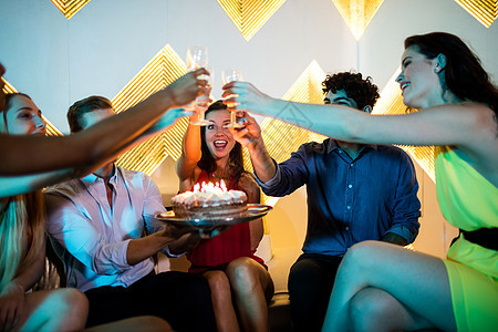 一群笑笑的朋友们在庆祝生日时 为一杯香槟举杯敬酒 女性 喝图片