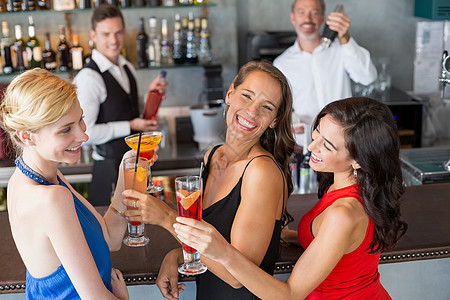 快乐的女朋友在酒吧柜台举杯鸡尾酒 漂亮的 派对图片