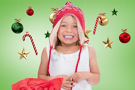 穿着编织羊毛帽的快乐女孩 微笑着与数字制作的圣诞节装饰图片