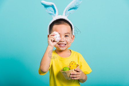 男孩穿兔子耳朵和黄色T恤衫 站立在霍尔 复活节彩蛋图片