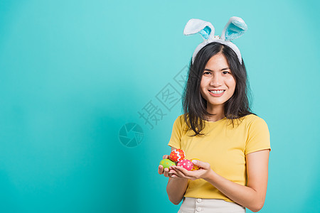 女人笑着穿着黄色的T恤 用兔子耳朵和小圆圈站立 手 微笑图片