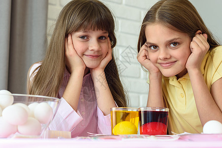两个女孩正在等待着复活节用不同颜色的彩蛋涂上两个鸡蛋图片