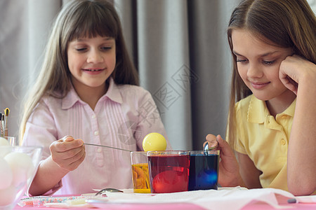 儿童用含液体染色剂的眼镜在复活节鸡蛋上涂漆图片