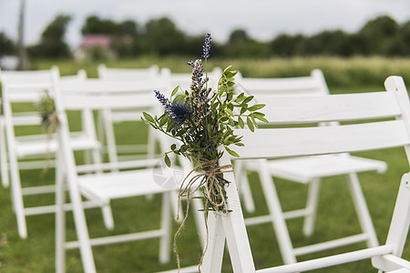 白婚席上装饰着绿色草地上的鲜花 为花园绿草坪的客人准备了空木质椅子 用于举行婚礼仪式 庆典 座位图片