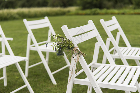 白婚席上装饰着绿色草地上的鲜花 为花园绿草坪的客人准备了空木质椅子 用于举行婚礼仪式 树 自由的图片