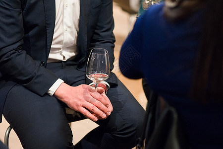 坐在套房的男子拿着一杯白葡萄酒 在一次美酒品尝活动上拍摄了身体部位的照片图片