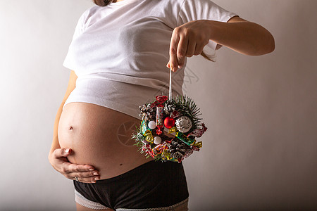 孕妇微笑 抚摸她的肚子 站在白墙上 复制空间 圣诞节 新年概念 父母 爱图片