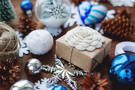 圣诞节和新年背景 木制背景上有礼物 丝带 球和不同的蓝色装饰品 用牛皮纸包装的礼品 带有手工钩针花 DIY 包装礼物的方法 假期图片