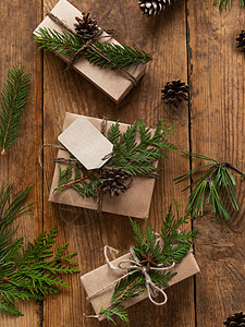 用牛皮纸包裹的圣诞礼物 以天然杉树和崖柏树枝作为装饰 木桌上的顶视图与手工制作的新年礼物 自然 枞树图片